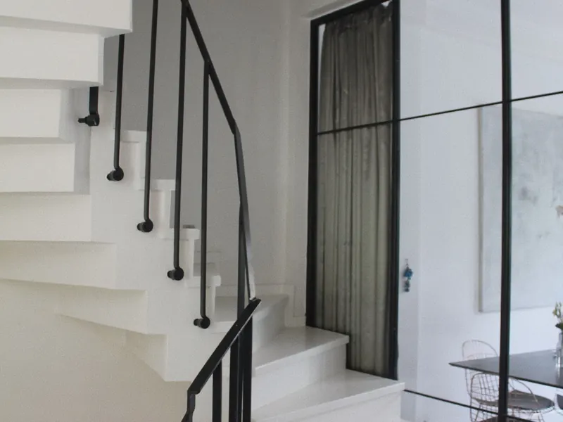 Escadaria branca com corrimão preto num edifício